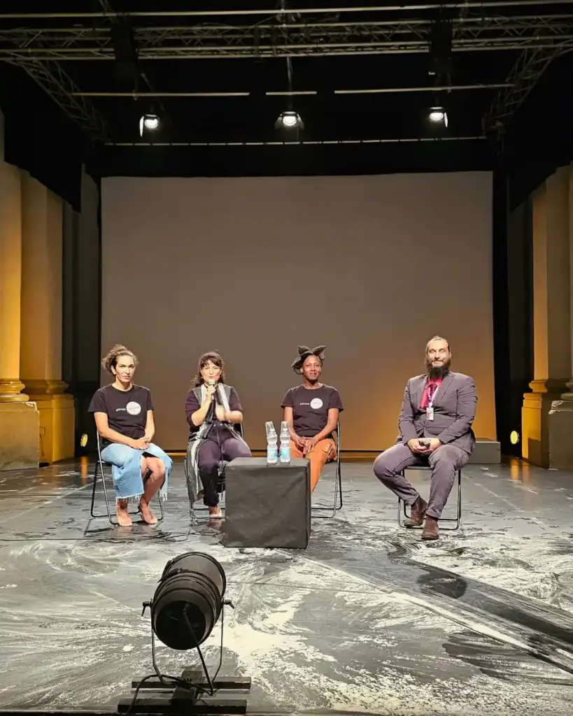 A post-performance talk on stage at Hangartfest 2026 featuring choreographer Aïda Colmenero Díaz, artists, and artistic board member Paolo Paggi seated in a row with microphones.